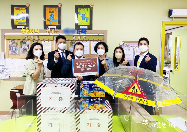 김앤장 법률사무소 임직원들이 어린이 안전 우산을 따뜻한 하루를 통해 아이들에게 전달하고 있다