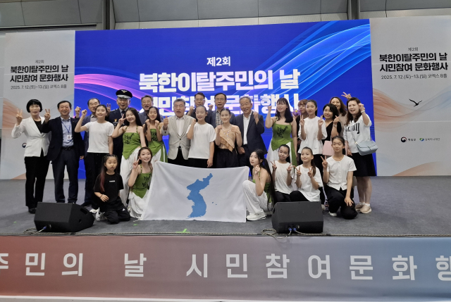 통일부 주최 ‘제2회 북한이탈주민의 날’ 시민 참여 문화행사(코엑스 B홀1 메인무대)에서 남북청소년중앙연맹 자유의 몸짓 - 청소년 통일댄스 공연을 마치고 연맹 정경석 총재, 홍양호 25년사 편찬위원장(명사), 이영하 명사, 설규종 명사, 김중태 명사, 전문교수진, 해외본부 편찬위원, 최종세 대기자 등과 함께 공연단(지도자 김혜숙, 단원 안지은, 장이정, 원세린, 김수아, 박태경, 박지은, 문정원, 김주연, 김민희, 김나경, 차소율, 박현경 이상 13인)이 기념 촬영을 하고 있다