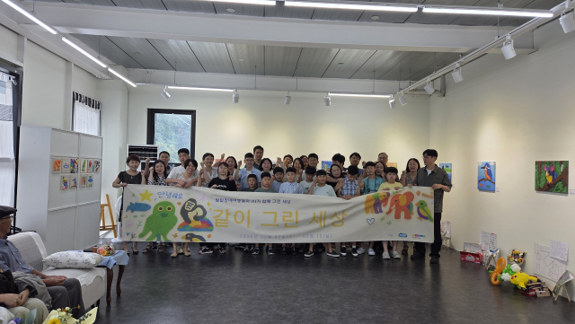 ‘모두의 창작’ 프로젝트 참가 아동들과 가족들, 영은하다 작가가 전시회 현수막 앞에서 기념 촬영을 하고 있다.