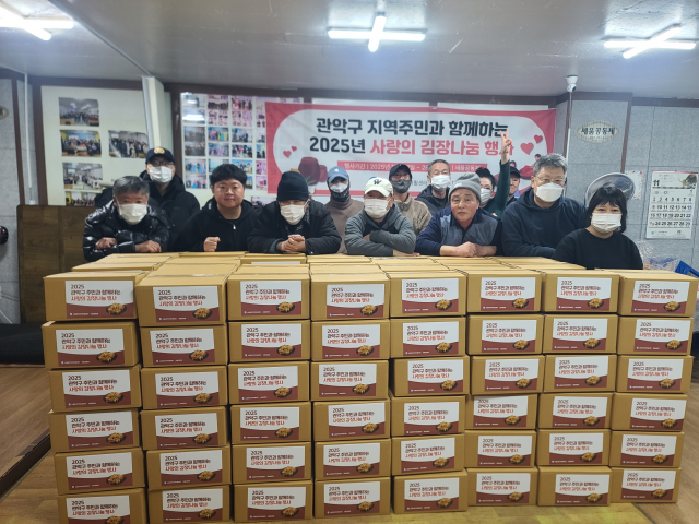 서울관악지역자활센터가 개최한 ‘2025년 관악구 주민과 함께하는 사랑의 김장나눔 행사’ 참여자들이 김장김치 상자와 함께 기념촬영을 하고 있다