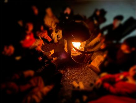 밤하늘 아래 캠프파이어를 둘러싸고 진솔한 대화를 나누는 청소년들과 사례관리자의 모습