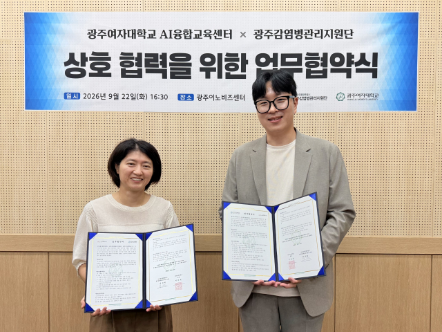광주감염병관리지원단장과 광주여자대학교 AI융합교육센터장이 상호 협력을 위한 업무협약 체결 후 협약서를 들고 기념촬영을 하고 있다