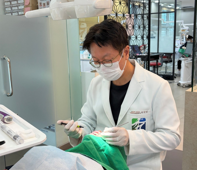 꿈을이루는수치과 유석민 원장이 환자의 치아를 레진으로 수복하고 있다
