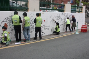 부산사회복무교육센터 벽화봉사동아리가 지역 주민들을 위해 허름한 벽면에 그림을 그리고 있다. (사진제공: 한국보건복지인력개발원 부산사회복무교육센터)