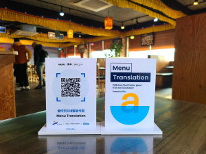 플리토 AI 메뉴 번역 서비스를 이용할 수 있는 QR 스탠드가 안산시 다문화음식문화거리 내 위치한 음식점에 설치된 모습