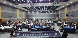 참석자들이 ‘세상을 향한 작은 빛의 하모니’라고 적혀 있는 현수막을 들고 단체 기념 촬영을 하고 있다