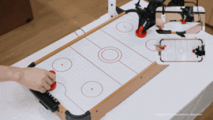 A robot powered by LingBot-VA 2.0 engages in a real-time tabletop air hockey match with a human