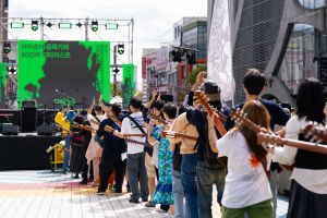 2024년 FESTIVAL THE SUB에서 진행된 ‘아마츄어 증폭기와 50인의 기타리스트’ 공연 참가자들이 기타를 들고 홍대 거리의 무대를 향해 줄지어 서 있다. 공연자와 관객의 경계가 느슨해지는 이 장면은 홍우주가 만들어온 ‘함께하는 판’을 상징적으로 보여준다(ⓒ 윤여은 @iiieungiiieung, 홍우주)