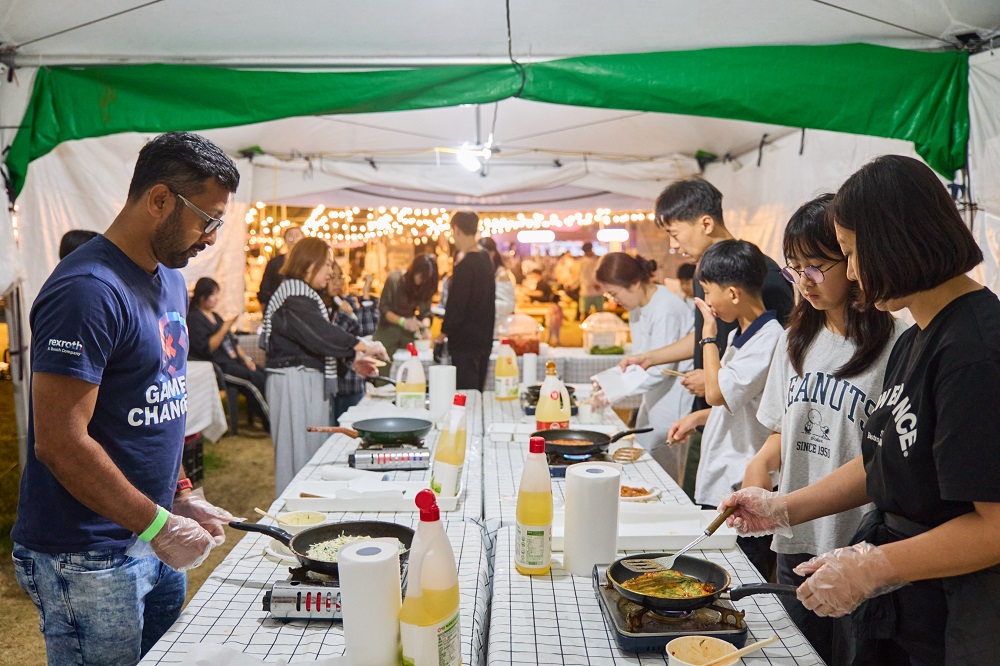 Visitors making Korean jeon pancakes at a cooking activity at the 2025 Starry Night Busan Night Market.