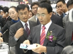 15일 부산 벡스코 전시장에서 개막한 'APEC 2005 IT전시회'의 삼성전자 부스에 진대제 정통부 장관이 방문, 삼성전자가 세계 최초로 개발한 휴대폰 타입의 