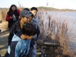 망원경을 통해 습지를 관찰하고 있는 청소년들