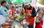 인사동 거리를 관광하던 외국인들이 KTF 김치 알리미 활동에 참석하여 직접 김치를 담그고 맛을 보며 즐거워하는 모습