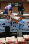 아시아나항공 강주안 사장 (좌측아래)이 일사일촌 마을인 외삼포2리에 사료 300포를 전달하고 있다.