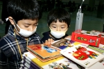 ‘제21회 서울국제유아교육전’을 찾은 두 형제가  ‘노벨과 개미’ 부스에서 마스크를 쓰고 놀이책을 살펴보고 있다.