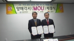 금경수 원광대학교 전통의학연구소 연구소장(왼쪽)과 오른쪽 김윤식 시흥시 시장이 양해각서를 내보이며 포즈를 취하고 있다.