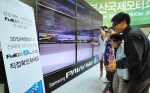부산 해운대 벡스코에서 열리는 '2010 부산국제모터쇼'를 관람하기 위해 참석한 가족들이 55인치 9대로 구성된 삼성파브 대형 풀HD 3D LED TV 조형물을 