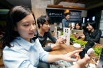 시민들이 ‘디초콜릿커피’ 압구정점 매장에 마련된 아이폰4 체험존에서 아이폰4와 테블릿PC를 이용해보고 있다.