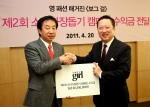 박용만 두산매거진 발행인(오른쪽)이 20일, 서울 중구 을지로6가 두산타워에서 전국소년소녀가장돕기 시민연합 중앙회 김성태 회장(왼쪽)에게 제2회 보그걸 핑크 윙즈(Pink Wing
