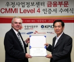 서광현 우정사업정보센터장(오른쪽)이 카네기멜론대학의 선임심사원 웨인 리틀필드(왼쪽)로부터 우체국금융부문 CMMI 레벨 4 인증서를 수여받고 있다.