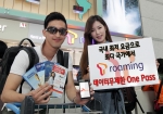 해외 여행을 준비하는 SK텔레콤 고객이 출국 전 공항에서 『T로밍 데이터무제한 One Pass』 서비스 가입을 한 뒤 웃고 있는 모습.