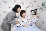 입원환자가 병상에 설치된 태블릿PC를 이용하고 있는 모습