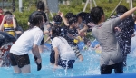 야외수영장에서 청소년들이 즐겁게 물놀이를 즐기고 있다.