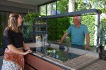 방문객이 LG 에코시티 정원 내 프리미엄 빌트인 시그니처 키친 스위트 제품들을 활용해 꾸며진 친환경 주방공간에서 냉장고를 체험하고 있다
