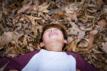 글꽃숲 참가 아동이 낙엽 가득한 숲에 누워 행복하게 웃고 있다