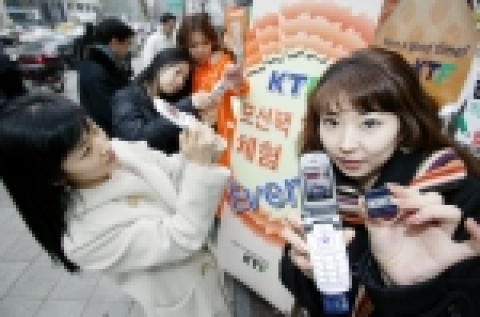 추운데 웅크려있지 말고 흔들면서 모바일 게임하세요!-휴대폰을 상하좌우로 움직이면서 게임을 조작하는 KTF의 모션팩 서비스를 고객이 직접 체험하면서 즐거워하고 있다.