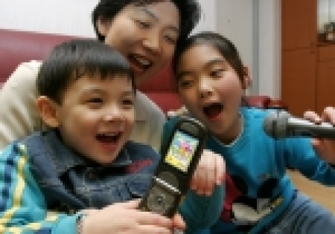 부모와 자녀가 함께 키즈랜드에서 어린이 동요인 ‘곰 세마리’를 다운로드 받아 함께 노래하며 즐거워 하고 있는 모습.
