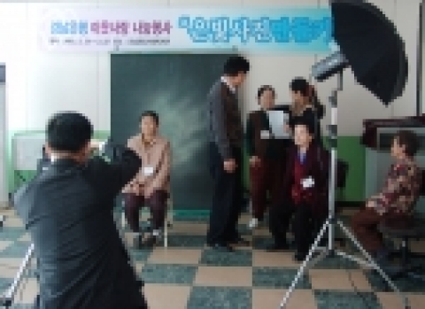 경남은행 직원이 노인분들의 영정사진을 찍고 있는 모습