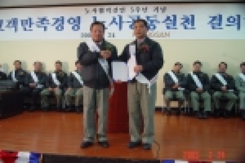 풍산 이문원 사장과 이상협 노조위원장이 결의문을 들고 악수하는 모습