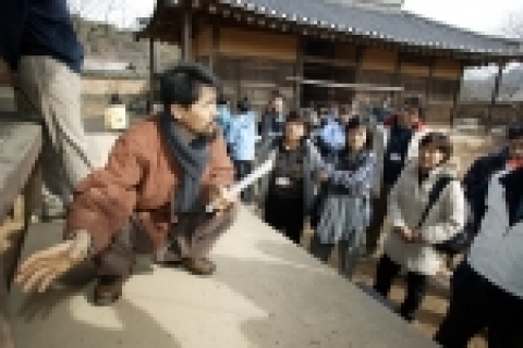 KTF 임직원으로 구성된 ‘백두대간 지킴이’들이 전통 집짓기 현장을 찾아 도편수(전통 집짓기를 총괄하는 목수)로부터 설명을 듣고 있다.