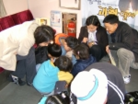 기차안에서 학부모와 학생들이 자기부상 팽이실험에 열중하고 있다. 