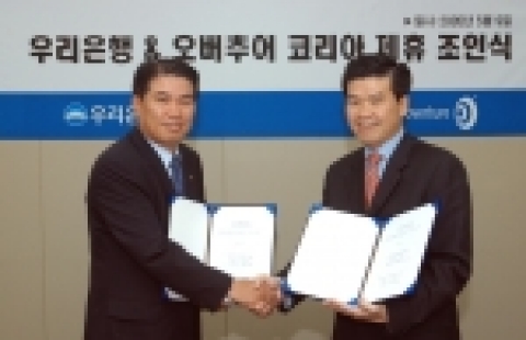 오버추어 코리아 김정우 사장(오른쪽)과 우리은행 카드사업본부 박정규 부행장이 조인식을 마치고 악수를 나누고 있다.