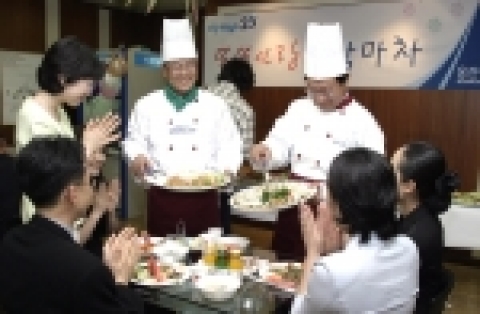 25일 웅진씽크빅 실내 포장마차에서 김준희 대표이사(좌)와 천재석 전무(우)가 생일을 맞이한 직원들에게 음식을 서빙하고 있다.