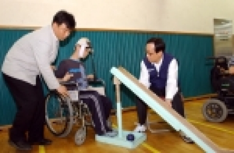 김신배 사장(오른쪽)이 뇌성마비 환자인 김근영 군(왼쪽)과 함께 보치아 경기를 하고, 경기용품을 전달하며 격려하는 모습