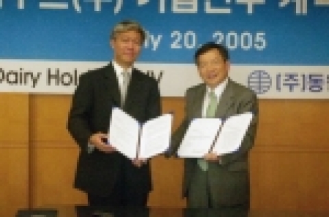 박인구 동원엔터프라이즈 사장(오른쪽)과 로이 콴(Roy Kuan) KDH(Korea Dairy Holdings) 매니징 디렉터(왼쪽)가 디엠푸드 인수계약서에 서명한 후 계약서을 들어 보이며 웃고 있다.
