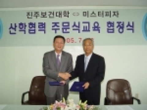 미스터피자의 황문구 대표와 진주보건대학 정종권 학장이 협정을 맺고 악수를 나누고 있다.