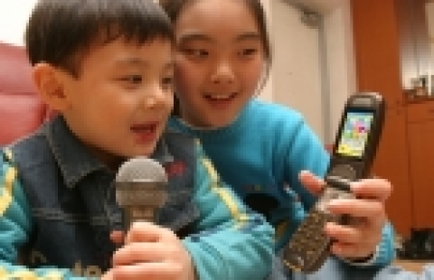 부모와 자녀가 함께 키즈랜드에서 어린이 동요인 ‘곰 세마리’를 다운로드 받아 함께 노래하며 즐거워 하고 있는 모습.