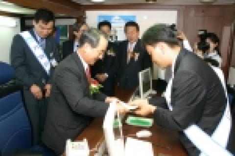 강권석 기업은행장(사진왼쪽) 이 1일 개점한 이동점포 U- finebank의 특수 제작된 차안에서 직접 통장을 발급받고 있다.