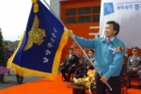 손학규 경기도지사가 남양주 소방서 개청식에 참석하여 소방서기를 흔들고 있다.