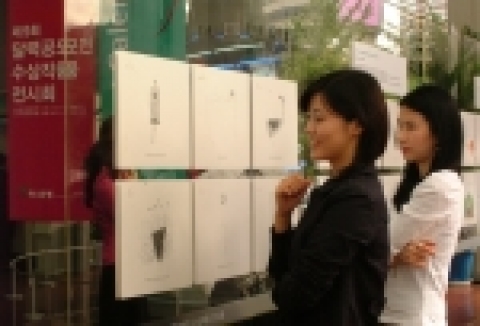 하나은행 본점 1층 로비에서 하나은행 고객들이 달력공모전 수상작을  감상하고 있는 모습임.