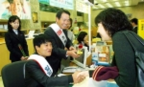 본점 영업부에서 차태현씨와 최원석 조흥은행 부행장이 고객들에게 기념품을 전달해주고 있는 장면