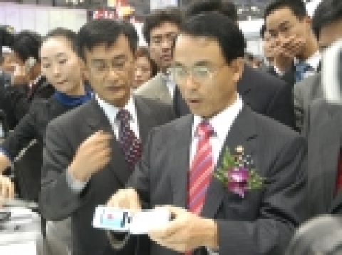 15일 부산 벡스코 전시장에서 개막한 'APEC 2005 IT전시회'의 삼성전자 부스에 진대제 정통부 장관이 방문, 삼성전자가 세계 최초로 개발한 휴대폰 타입의 와이브로 단말기를 살펴보고 있다.