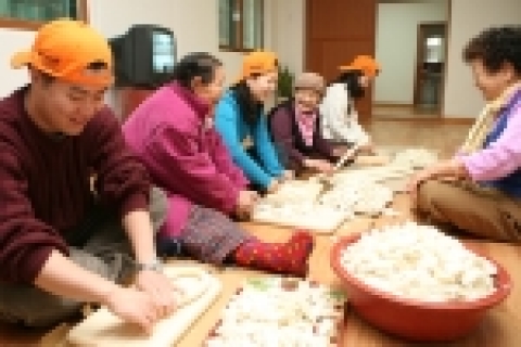 한국마이크로소프트 임직원들이 독거 어르신들과 함께 떡을 썰고 만두를 빚으며 즐거워 하는 모습.