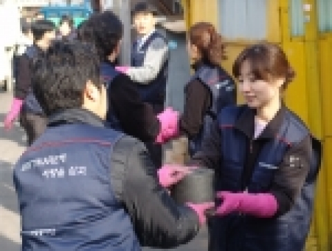 SW진흥원 직원들이 오르막길에서 릴레이 방식으로 연탄을 전달하고 있다.