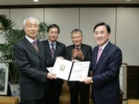 경남은행 정경득 은행장(오른쪽)이 대한적십자사 배경훈 경남지사장으로부터 대한적십자사 특별회원증을 받고 있다.