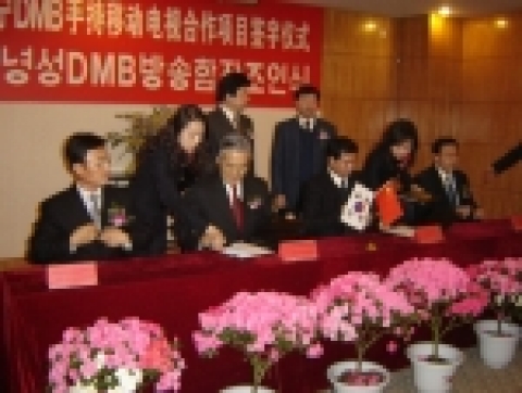 ETRI 임주환 원장(사진 중앙좌측)이 중국 요녕성 광전총국 리허우푸 국장과 DMB 조인식에서 서명하고 있다. 사진 맨좌측(앉은사람)이 심양해특고신기술 발전 유한공사 강인규 대표이