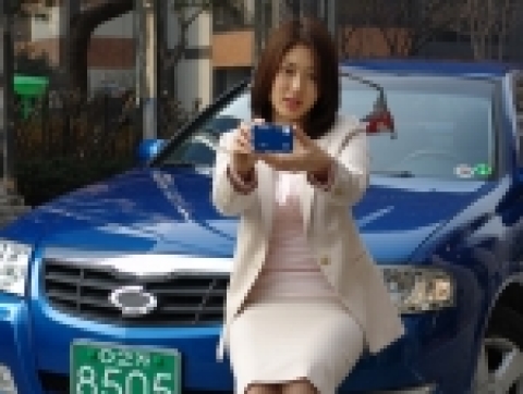 고객이 SM3 New Generation 앞에서 삼성 케녹스 디지털 카메라를 들고 있는 모습
